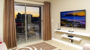 En stue med en skydedør til en balkon, et fladskærms-tv monteret på væggen og et hvidt tv-møbel nedenunder.