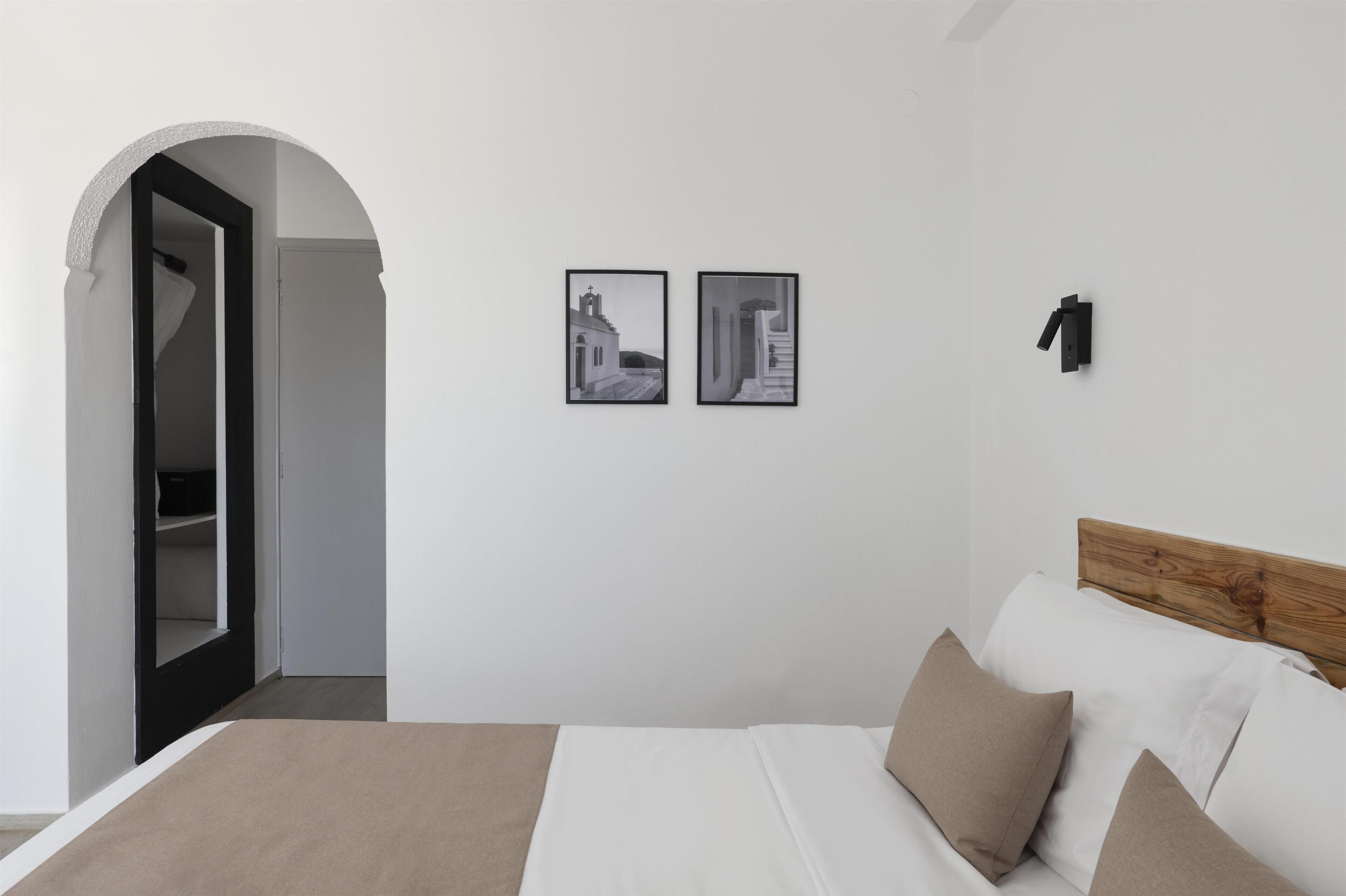 Une chambre à coucher avec un lit, une tête de lit en bois, une armoire et deux photographies en noir et blanc accrochées au mur.