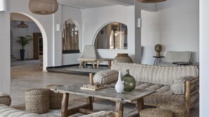A modern living room with a sofa, wooden coffee table, woven baskets, and a chessboard. - Pounda Resort Paros, a member of Radisson Individuals (Pounta)