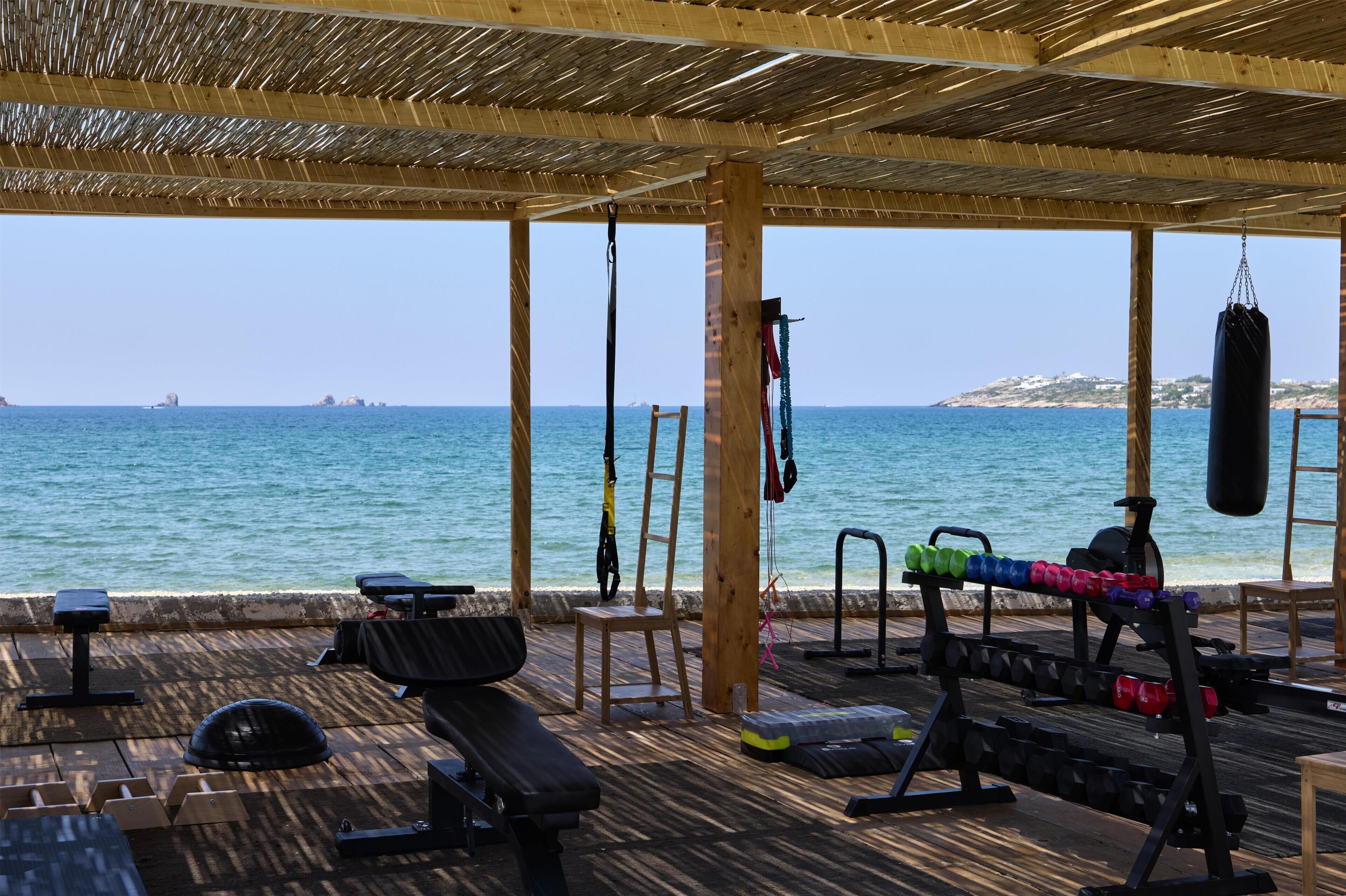 Une salle de sport en plein air équipée de divers appareils, avec un banc et une vue sur la mer.
