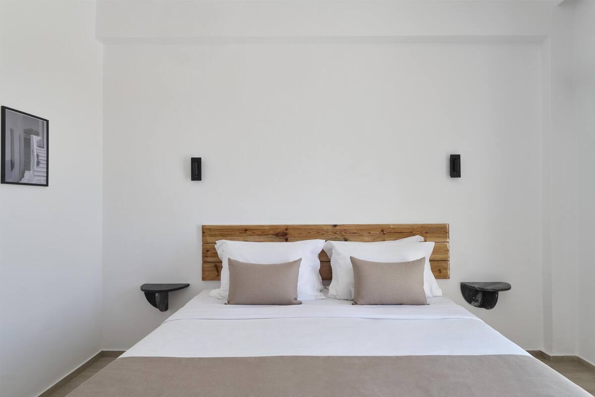 A bedroom with a wooden headboard, two bedside tables, and a framed picture on the wall.