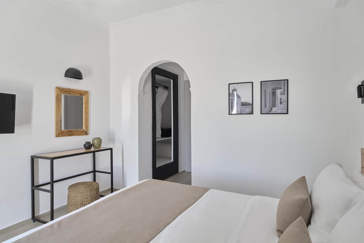 A bedroom with a bed, a console table, a mirror, and two framed pictures on the wall.