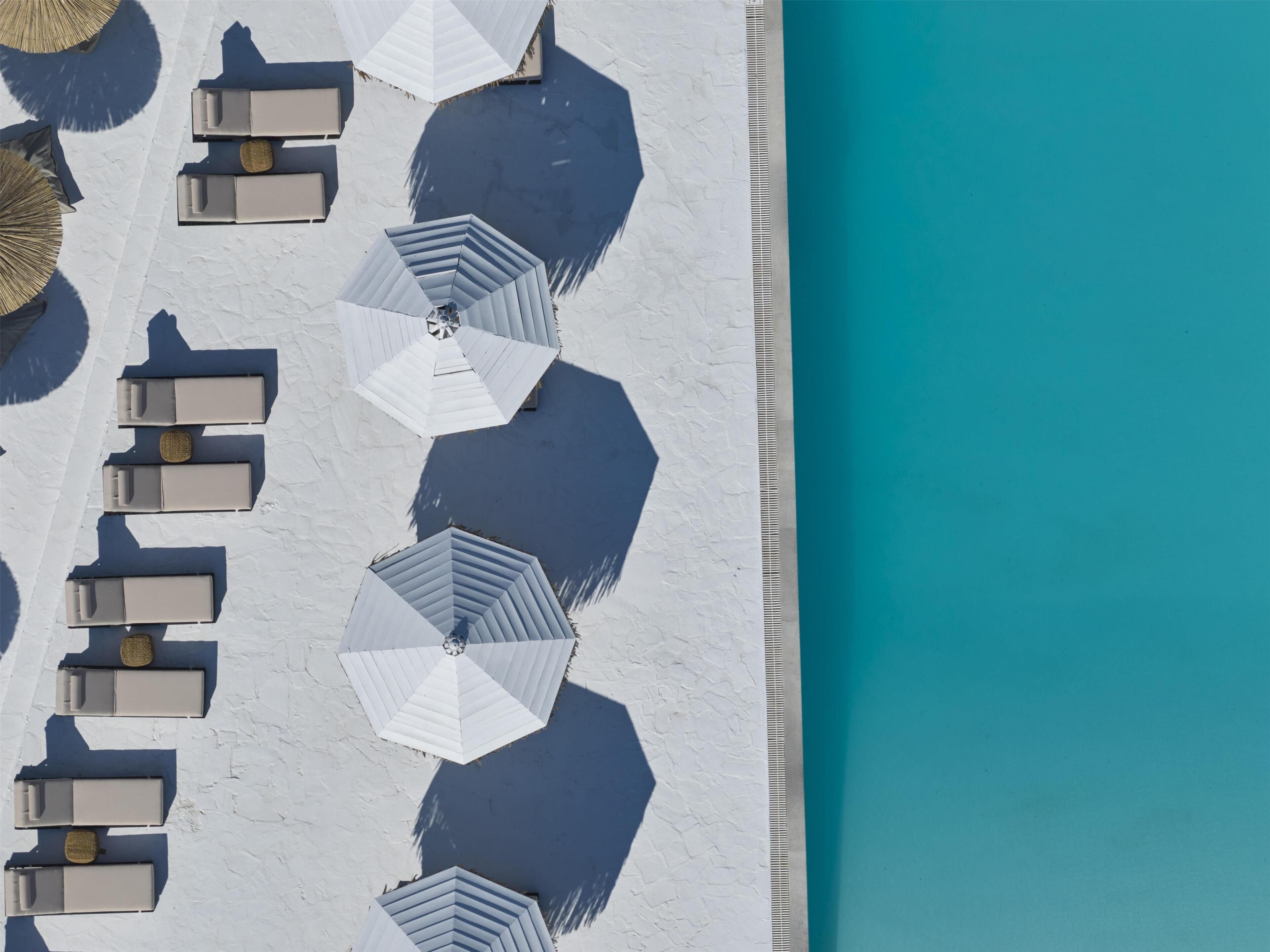 An aerial view of a beach with white umbrellas and lounge chairs arranged in rows.