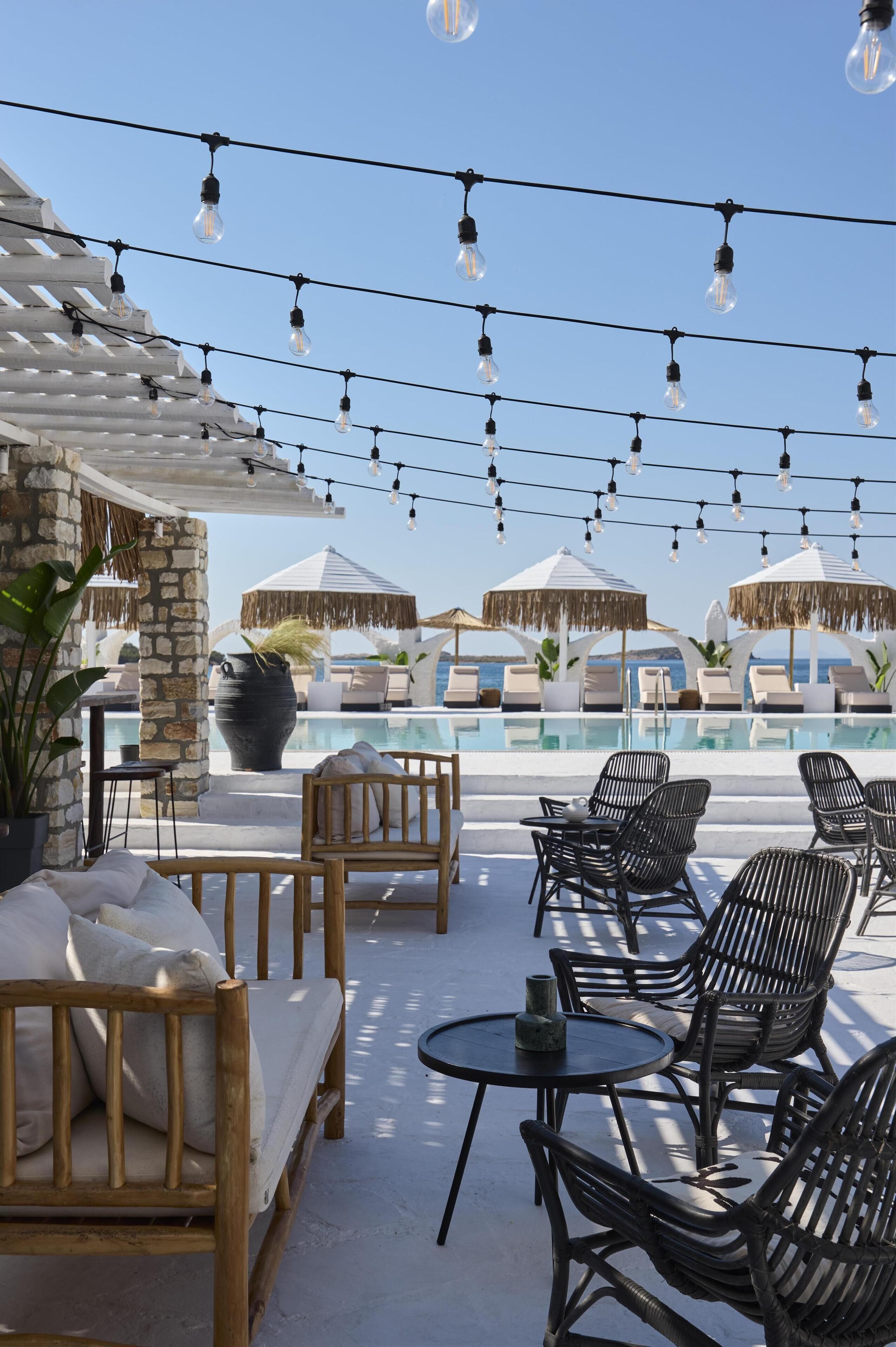 A rooftop pool area with lounge chairs, a stone pillar, and string lights.