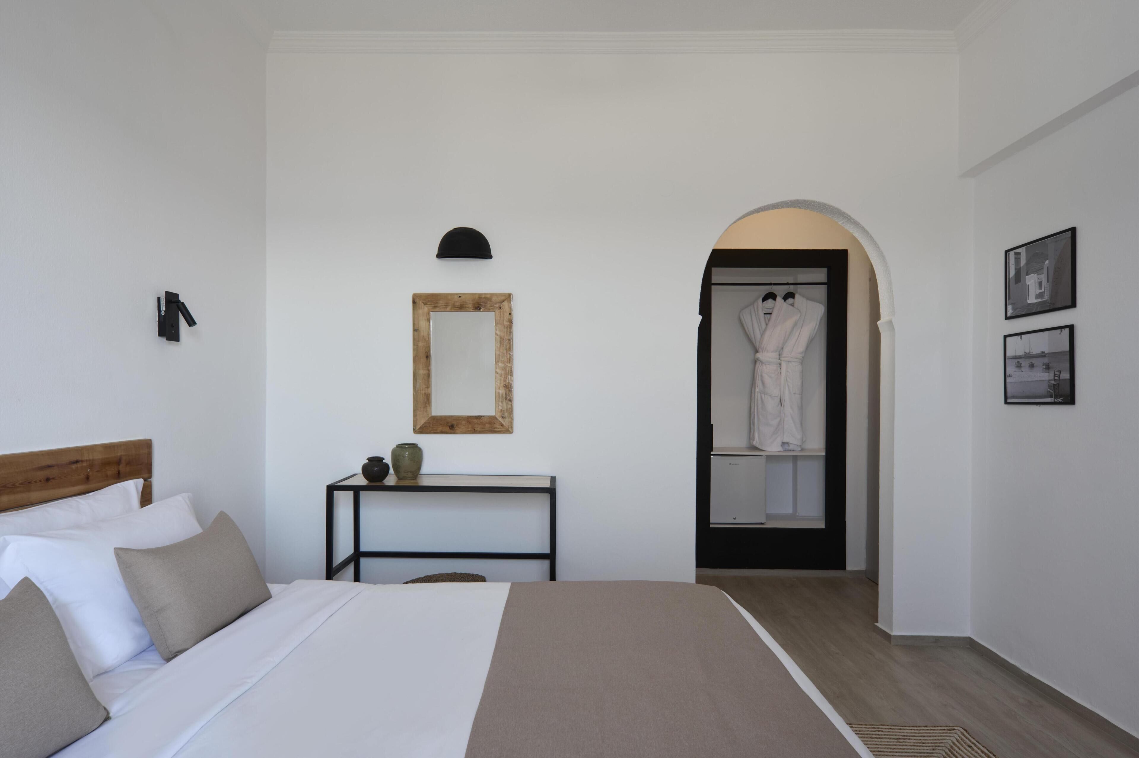 A bedroom with a bed, bedside table, mirror, and a robe closet.