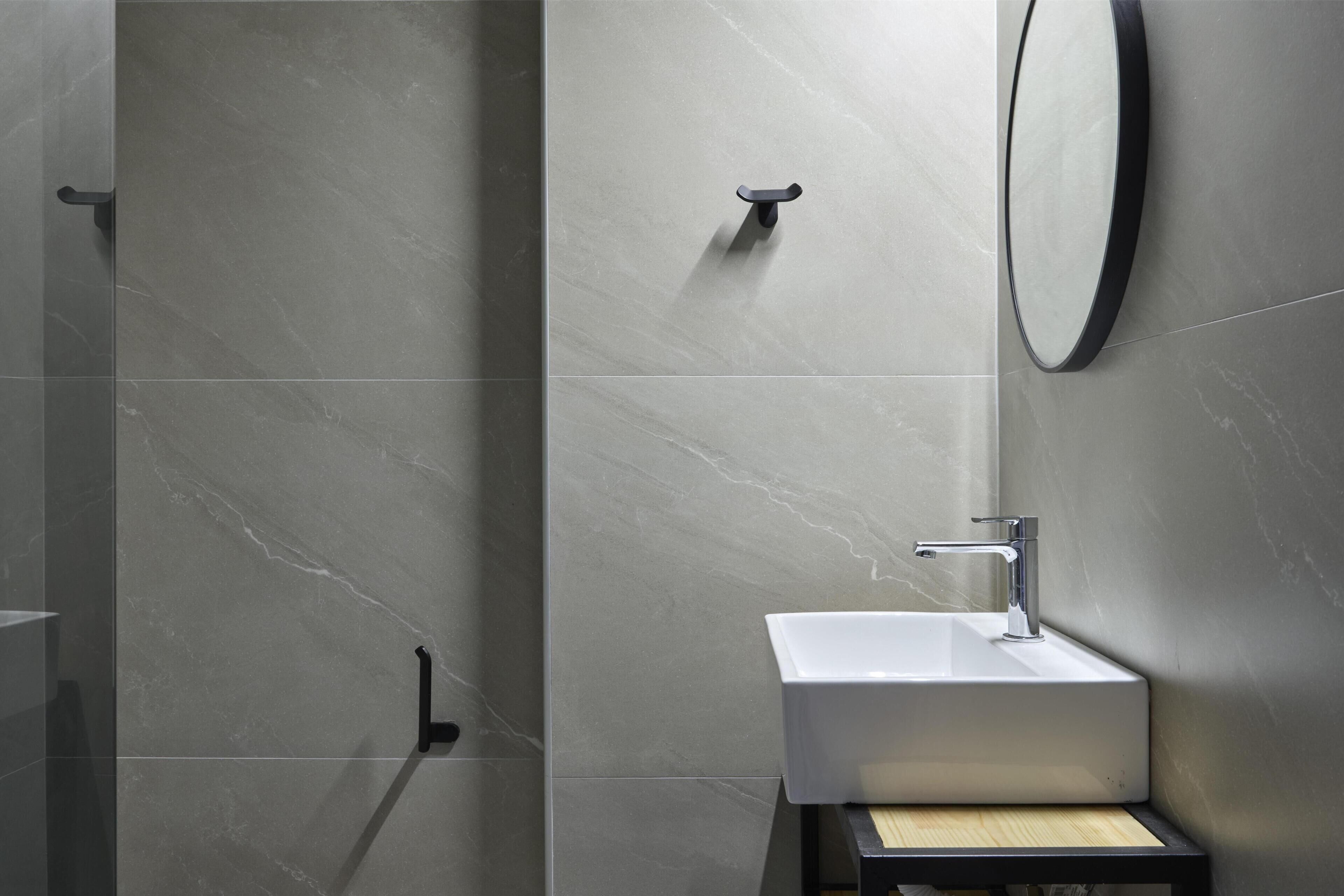Een moderne badkamer met een douche, wastafel en spiegel.