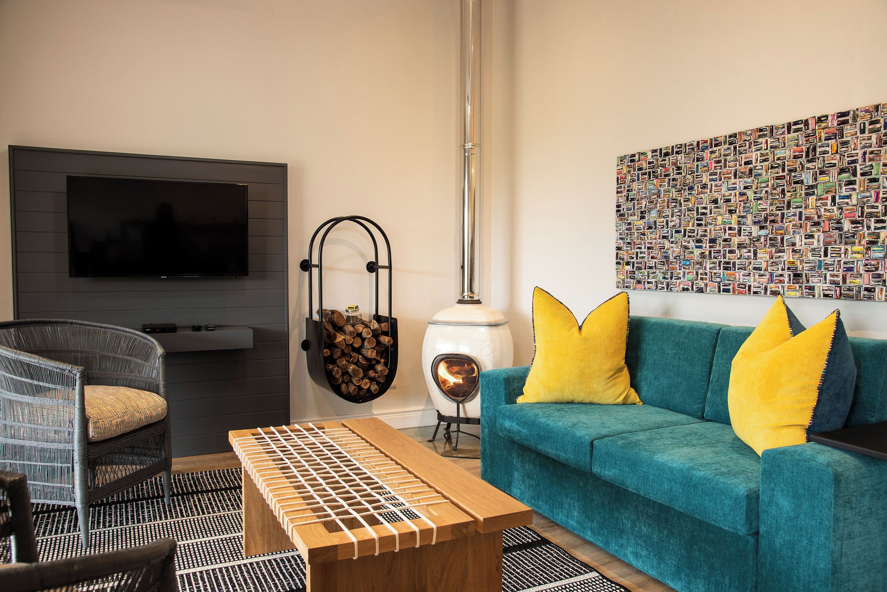 Una sala de estar moderna con televisor, un sofá con cojines amarillos, una mesa de centro de madera, una silla colgante y una chimenea empotrada en la pared.
