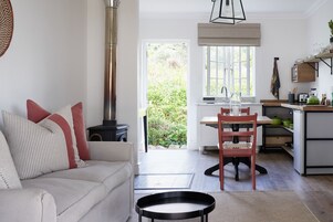 Una sala de estar moderna con un sofá, una mesa de comedor y una cocina equipada con estufa y encimera.