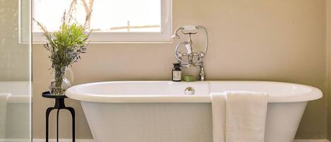 A bathroom with a freestanding bathtub, a window with a view of trees, and patterned floor tiles.