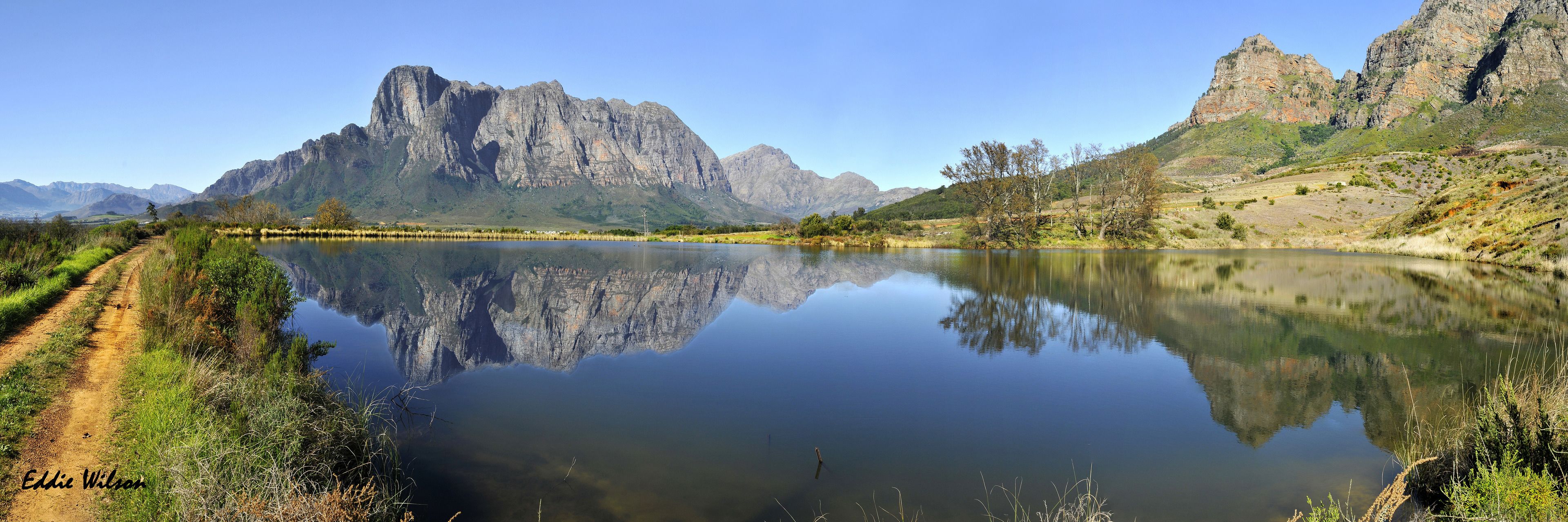 Paisaje de montaña con un lago tranquilo que refleja las montañas.