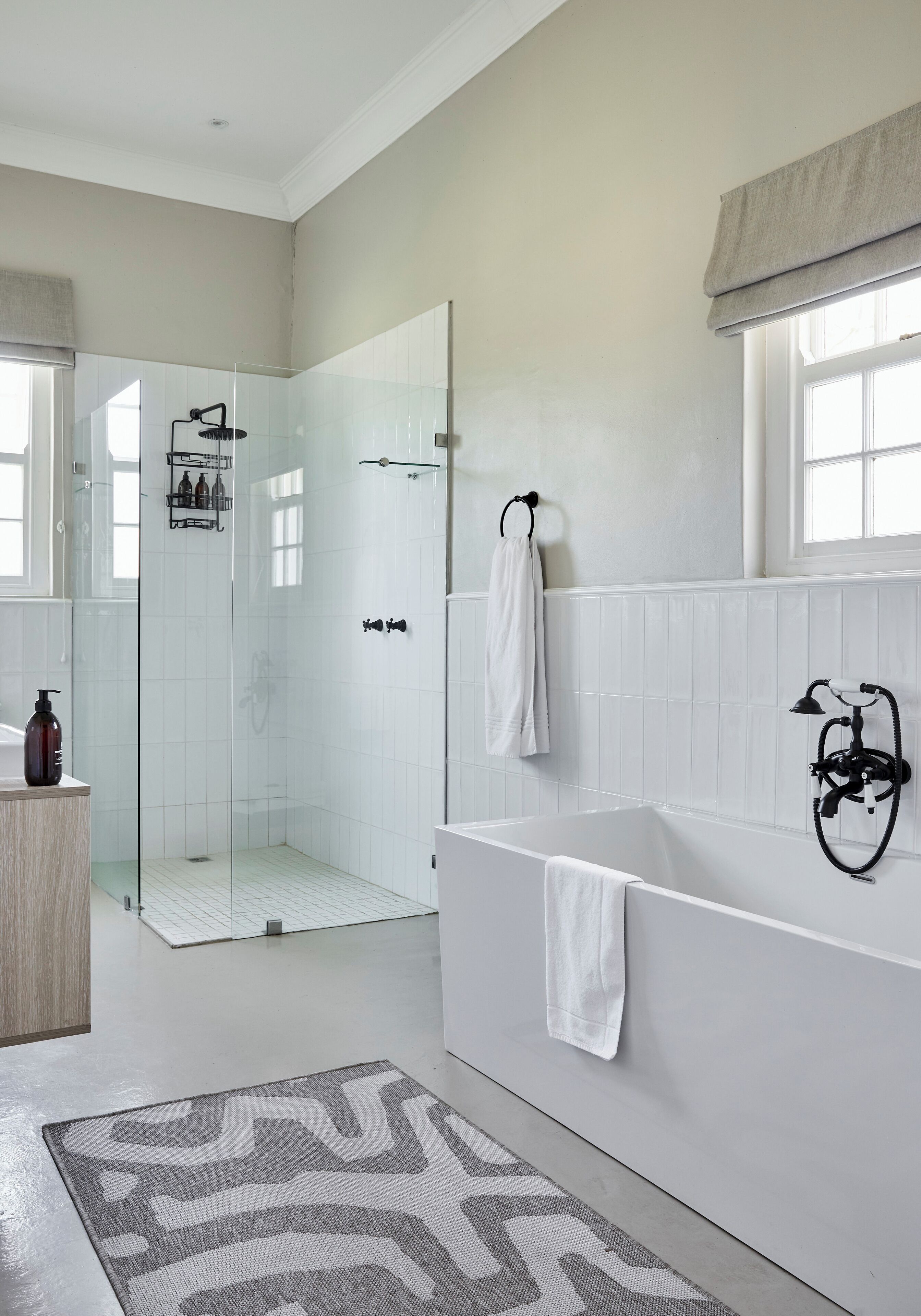 Une salle de bain moderne dotée d’une douche à parois de verre, d’une baignoire sur pieds et d’un meuble-lavabo avec un miroir.