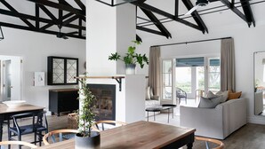 A spacious living area with a wooden dining table, chairs, a sofa, and a fireplace.