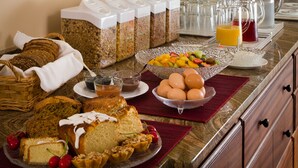 Een ontbijtbuffet met diverse gerechten, een koffiehoek en twee ingelijste schilderijen aan de muur.