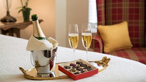 Een bed met een fles champagne, twee champagneglazen en een doos chocolade.