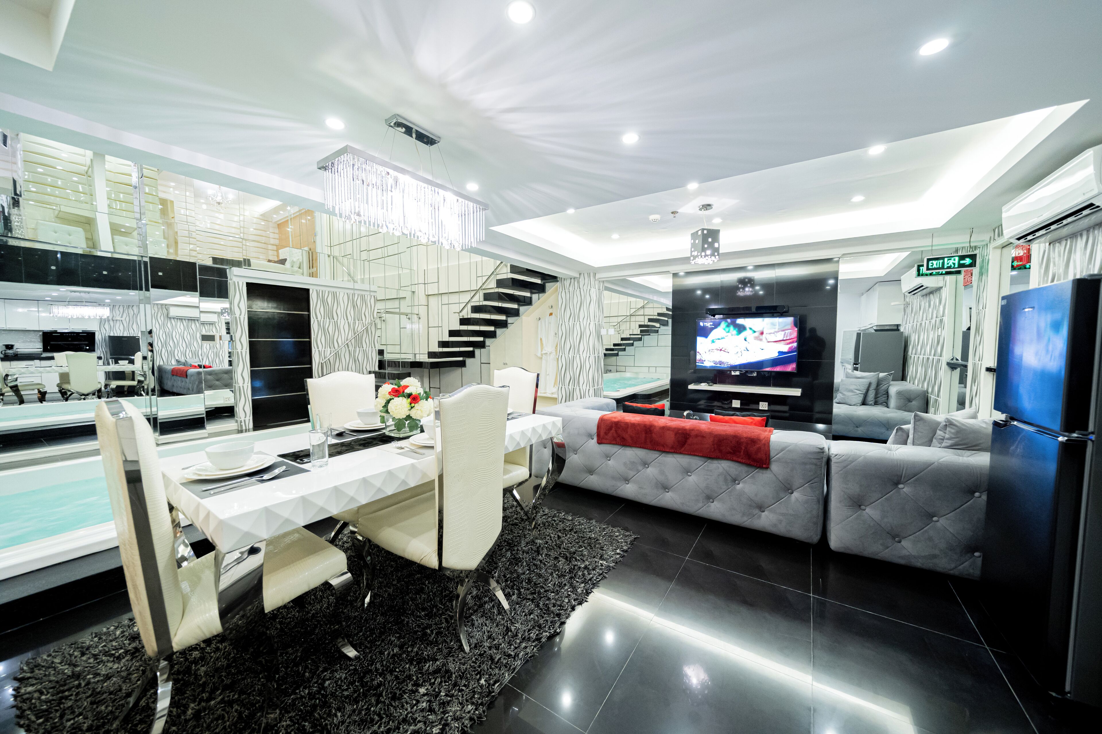 Una sala moderna con comedor, una escalera y un televisor.