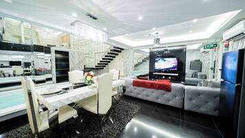 Una sala moderna con comedor, una escalera y un televisor.