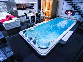 Quarto de hotel moderno com hidromassagem, área de refeições e cozinha.