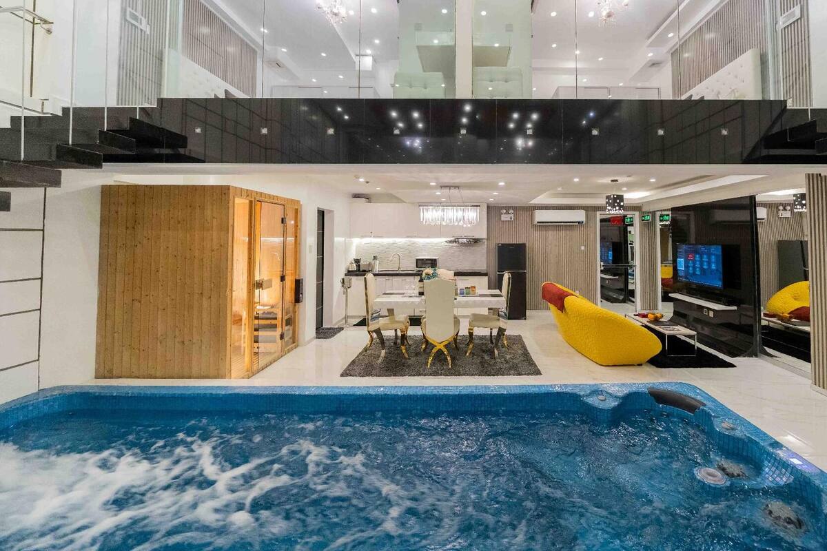 Un intérieur moderne avec une piscine centrale, un coin repas et un espace de vie doté d’un téléviseur.