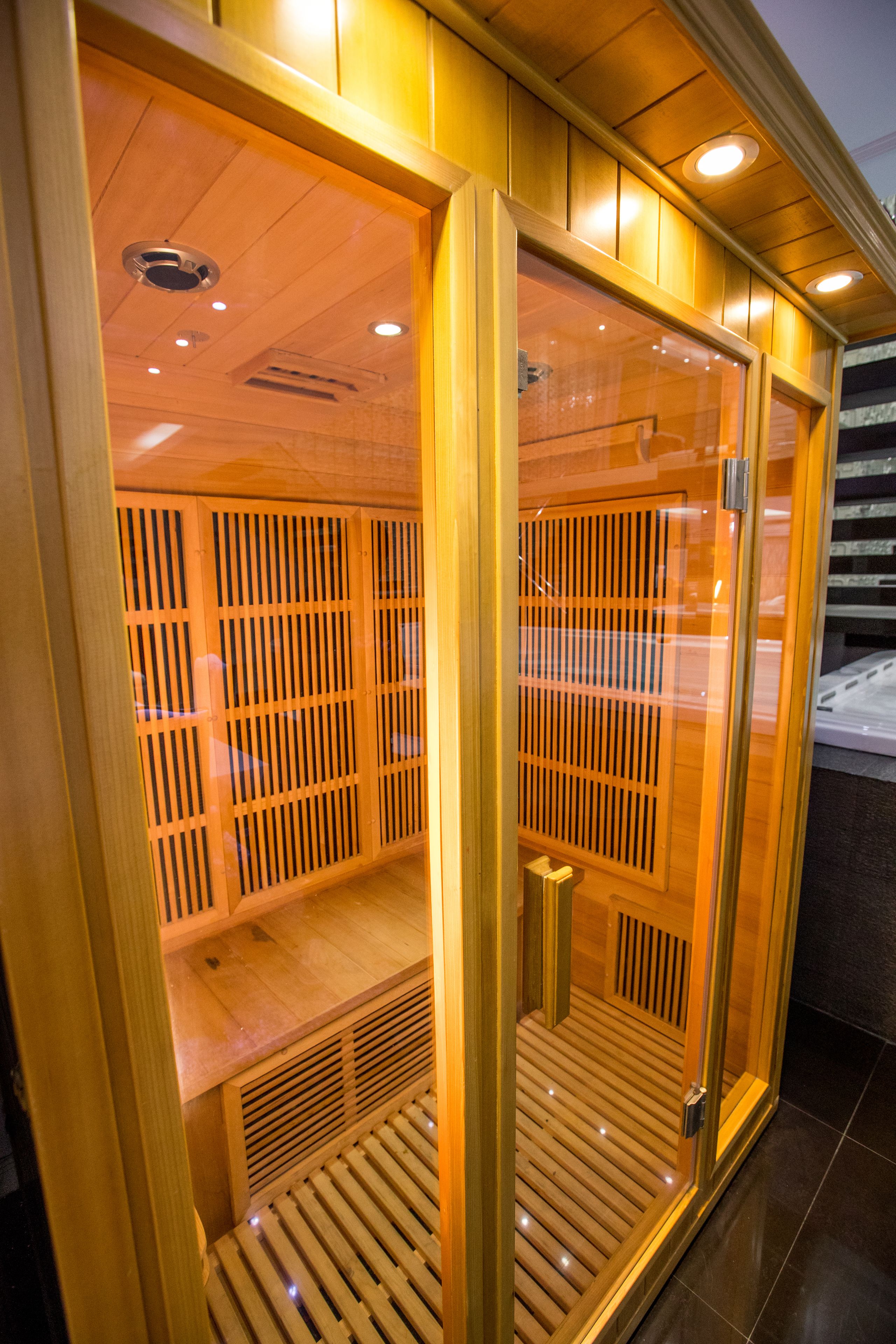 A sauna with wooden slats and a bench, enclosed by glass walls and wooden panels.