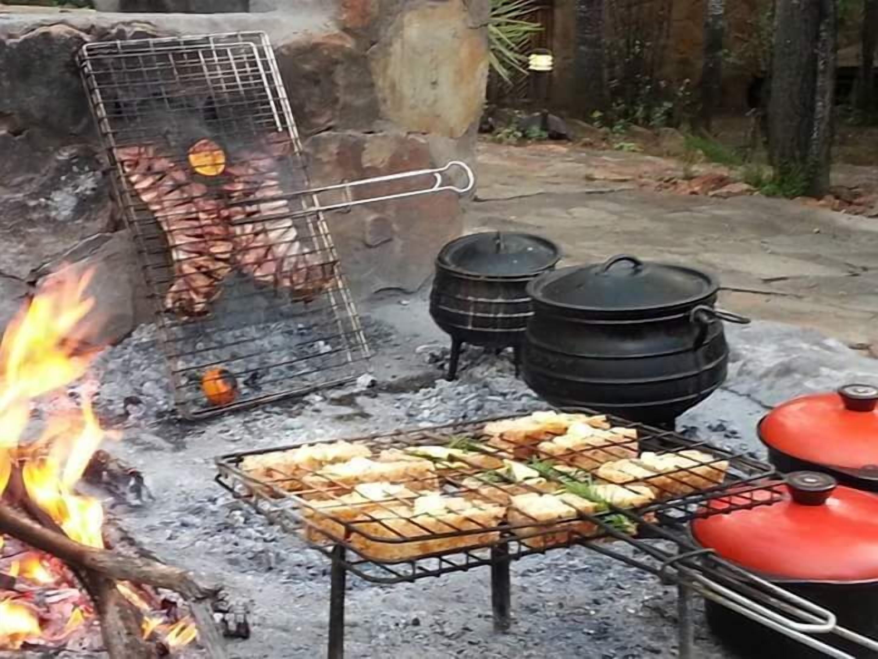 Ein Grillplatz mit Grill, Töpfen und Feuer.