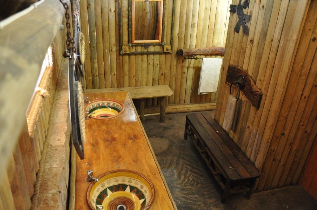 Una sala de sauna con paredes de madera, un banco y una mesa de madera con una palangana.