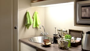 A kitchen with a sink, a coffee maker, and a tea pot on the counter.