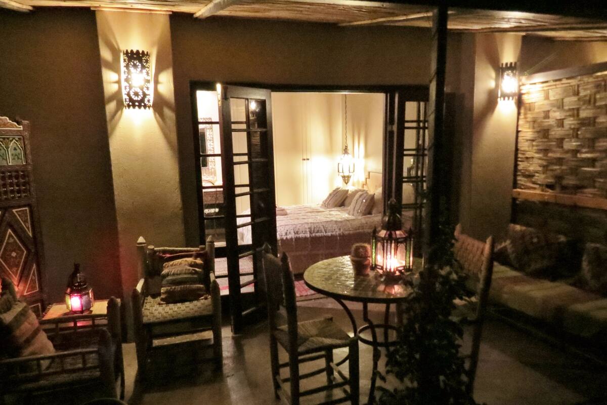 Una habitación acogedora con una cama, una mesita con un farol y un sofá.