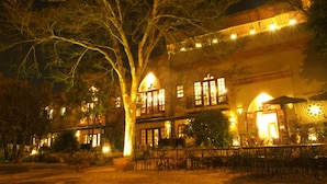 A building with multiple balconies, outdoor seating, and a large tree in the foreground.