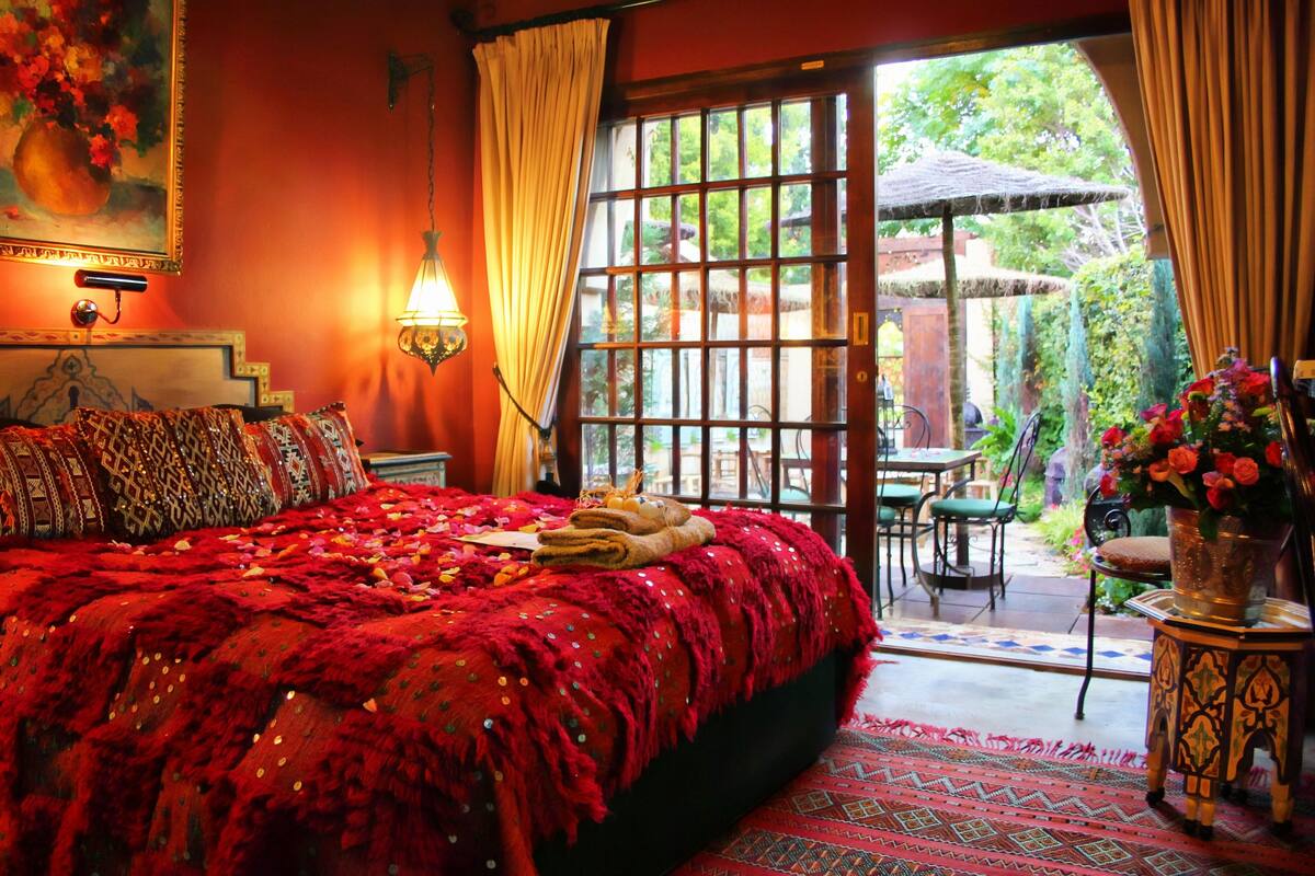 Una habitación con una cama grande, un comedor y vistas al jardín.