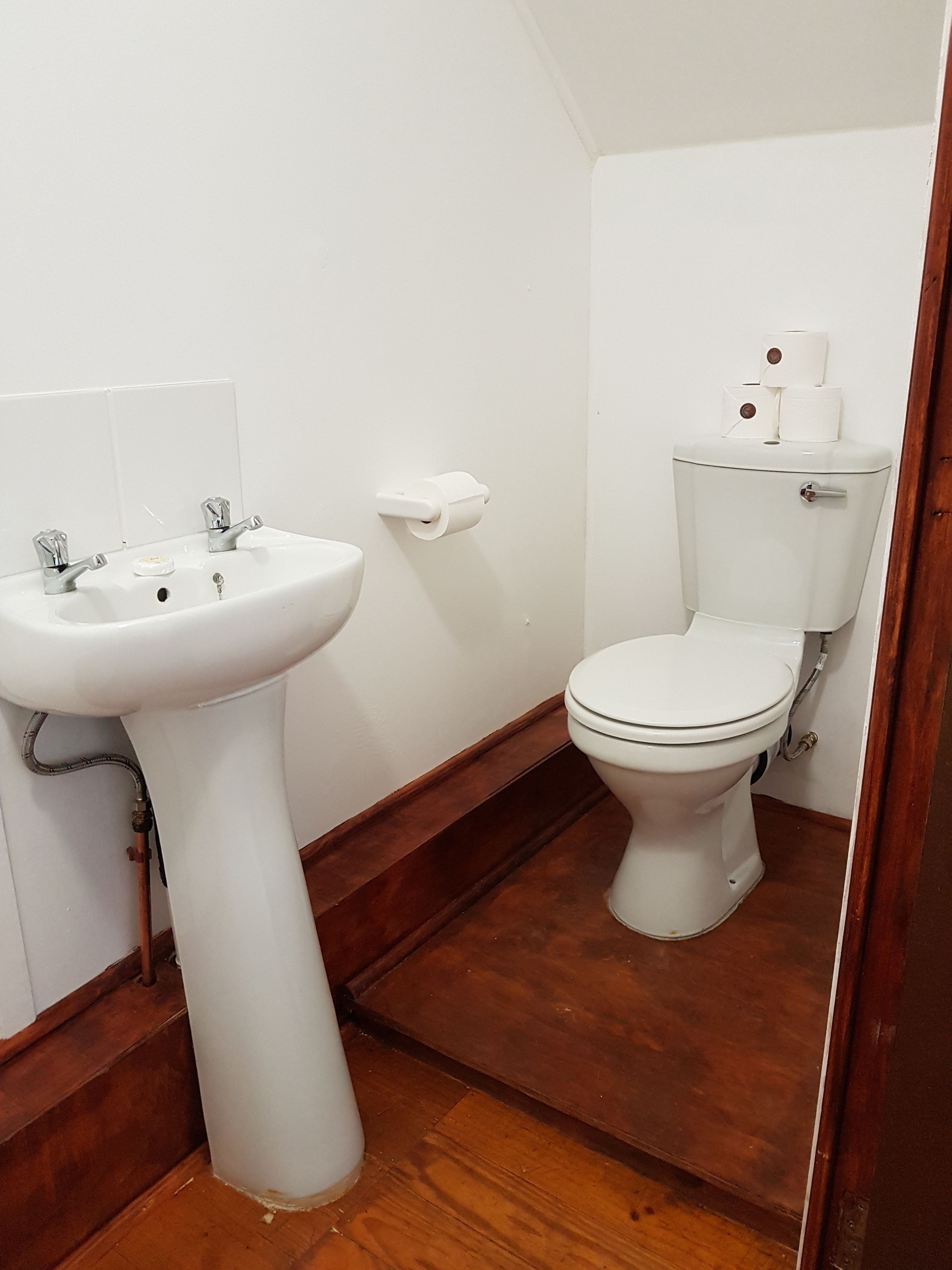 Ein Badezimmer mit Waschbecken, Toilette und Holzboden.