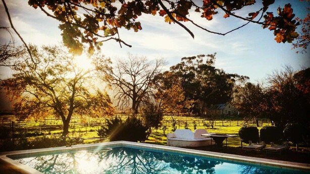 A swimming pool with a view of trees and a house in the background. - Montpellier De Tulbagh (Tulbagh)