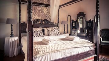 A four-poster bed with a canopy, a mirror, and a dresser with a mirror.