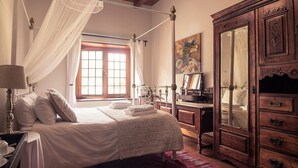 A bedroom with a four-poster bed, a wooden wardrobe, and a large window with curtains. - Montpellier De Tulbagh (Tulbagh)