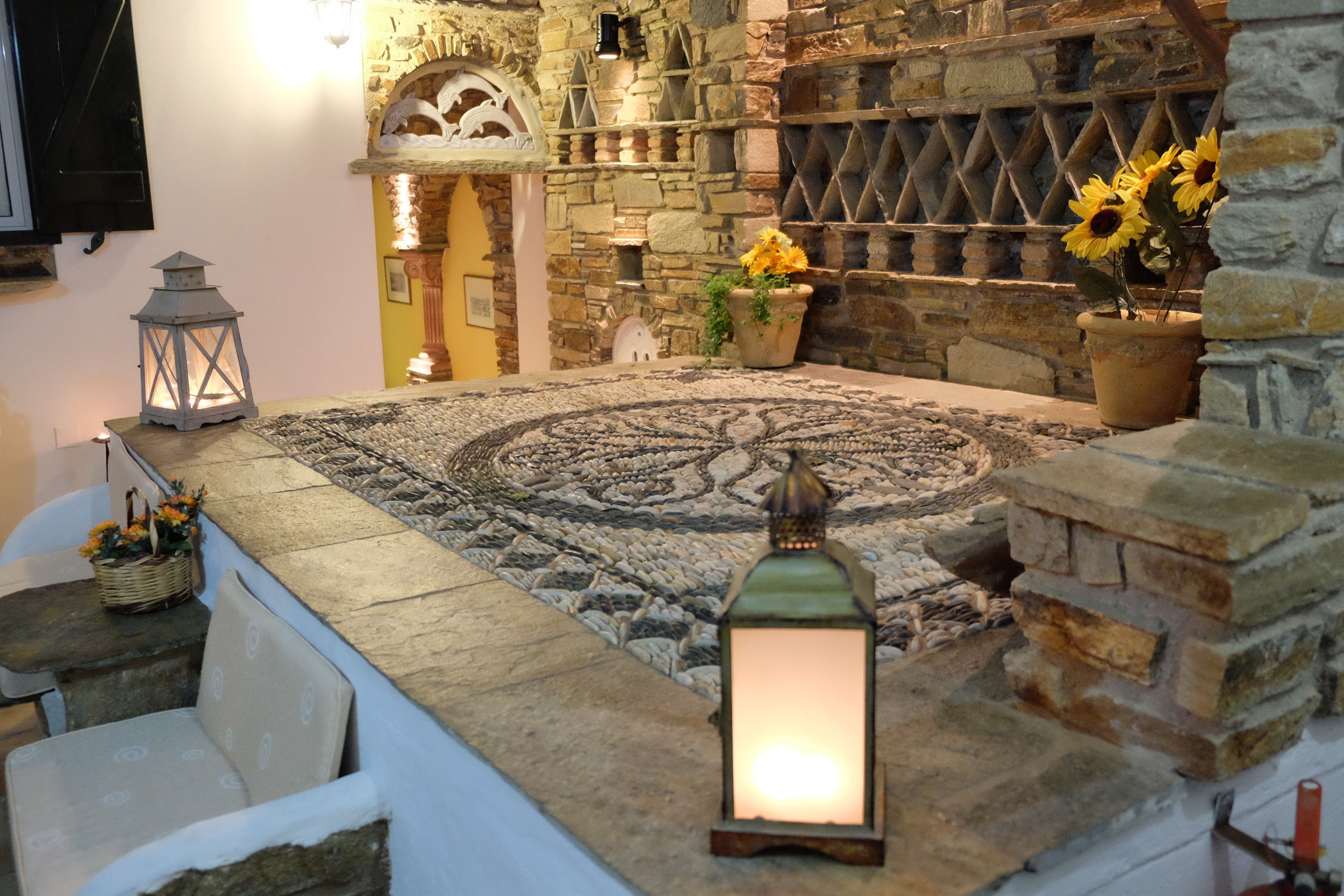 A stone fireplace with a patterned rug, a lantern, and potted sunflowers.