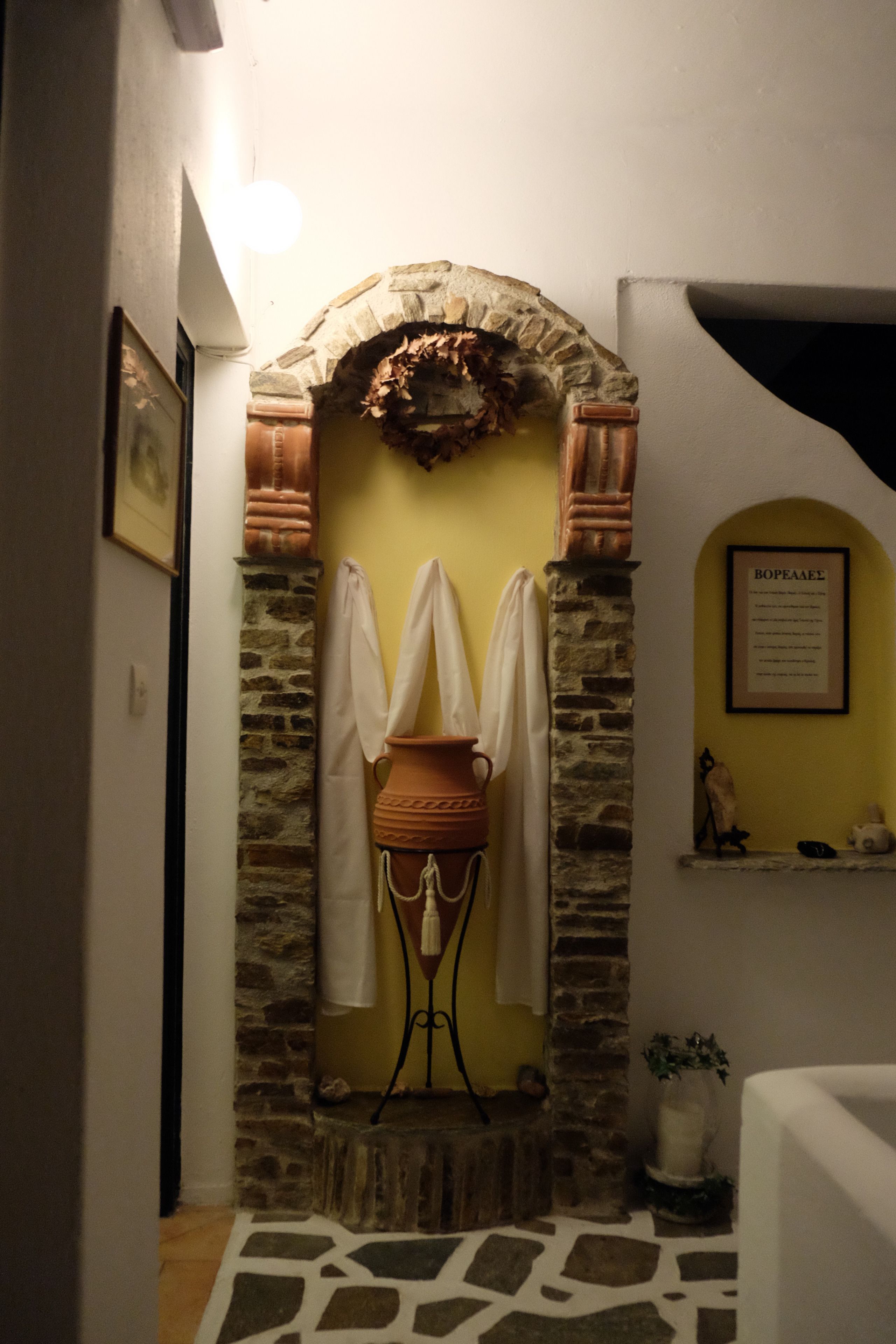 A bathroom with a stone archway, a white bathtub, and a small shelf with toiletries.