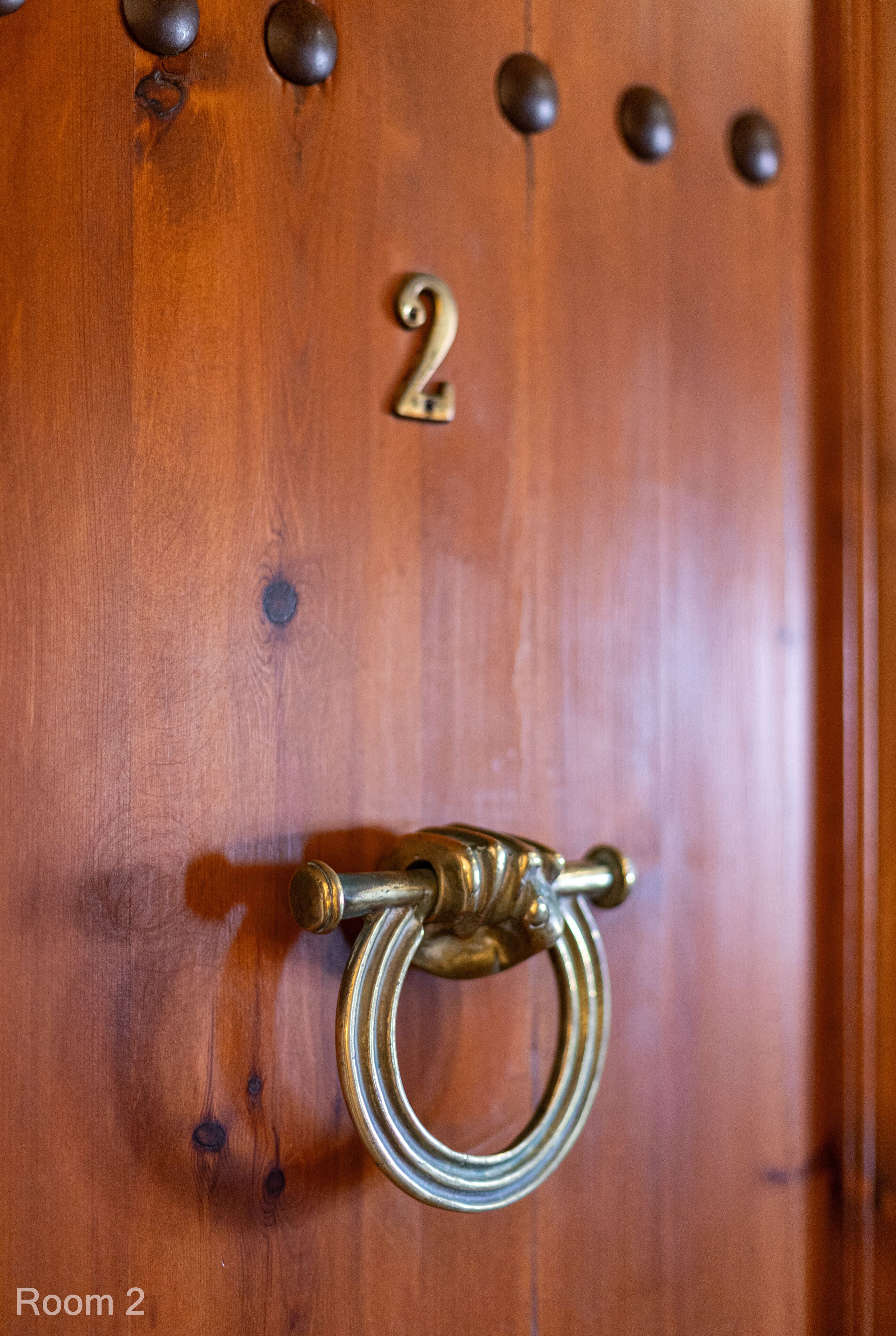 A wooden door with a brass door knocker and a number '2' above it.