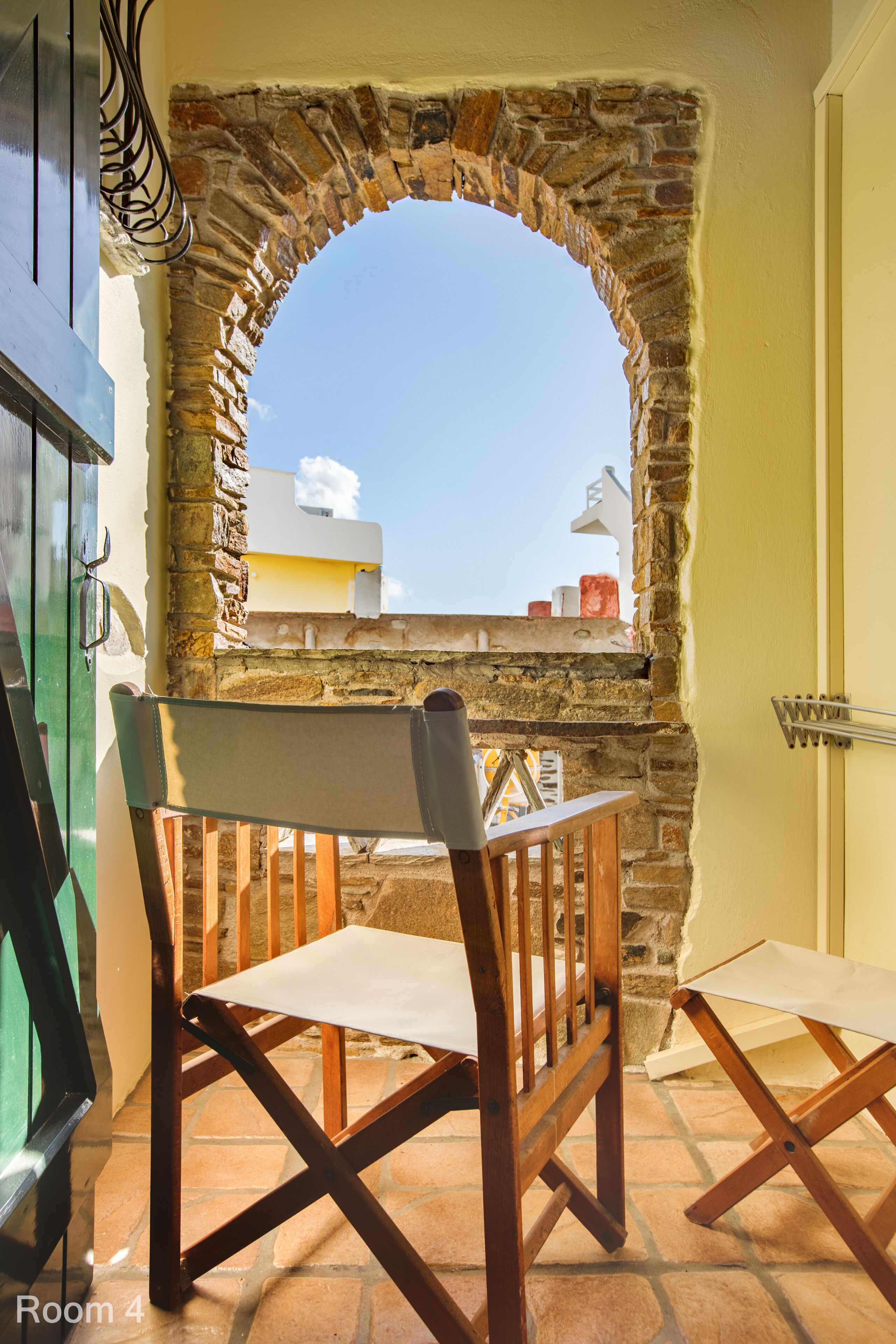 A room with a stone archway leading to a terrace, a wooden table, and two chairs.