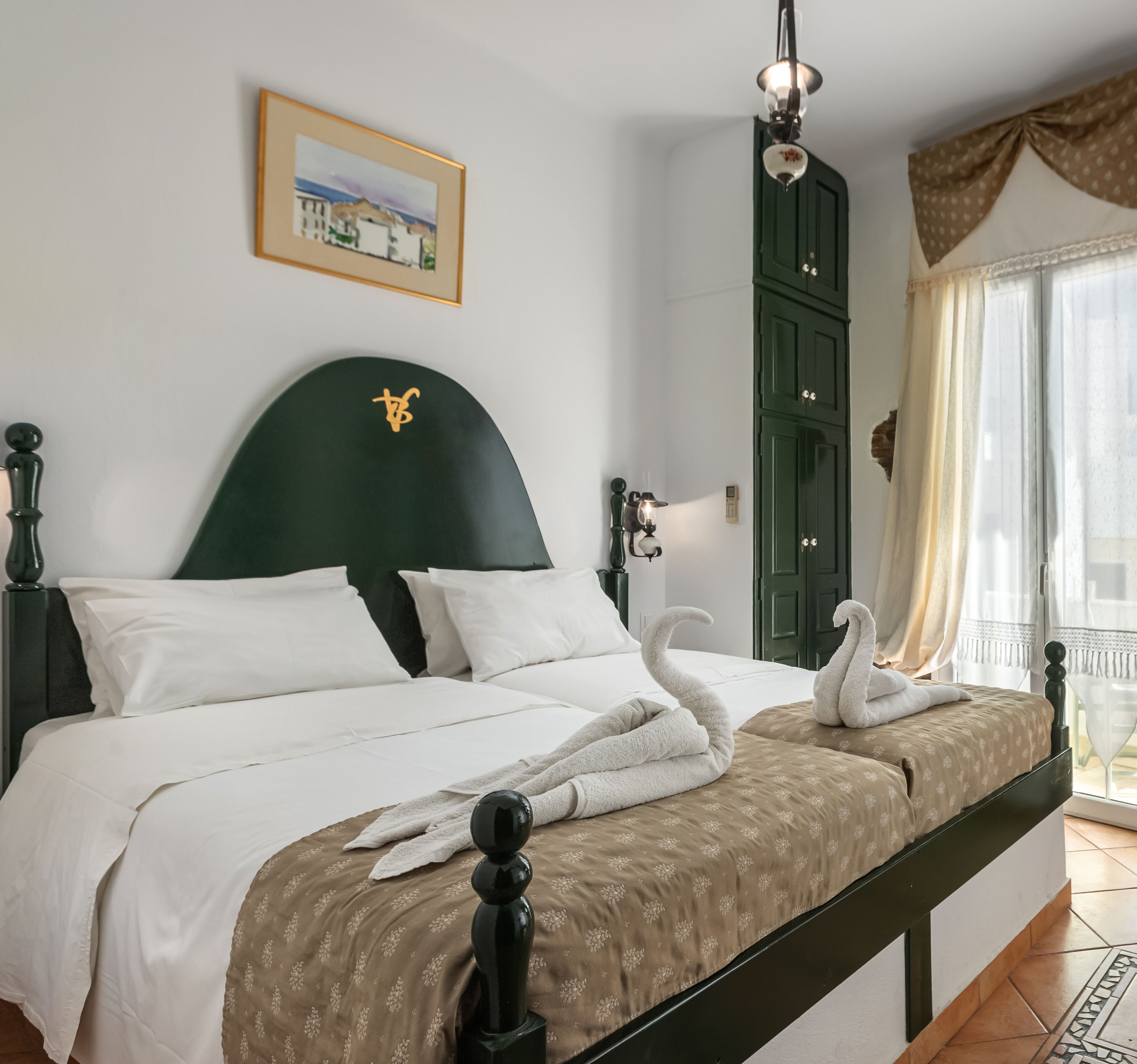 Una cama bien hecha con sábanas blancas y una colcha marrón estampada, un cabecero verde y un cuadro en la pared.