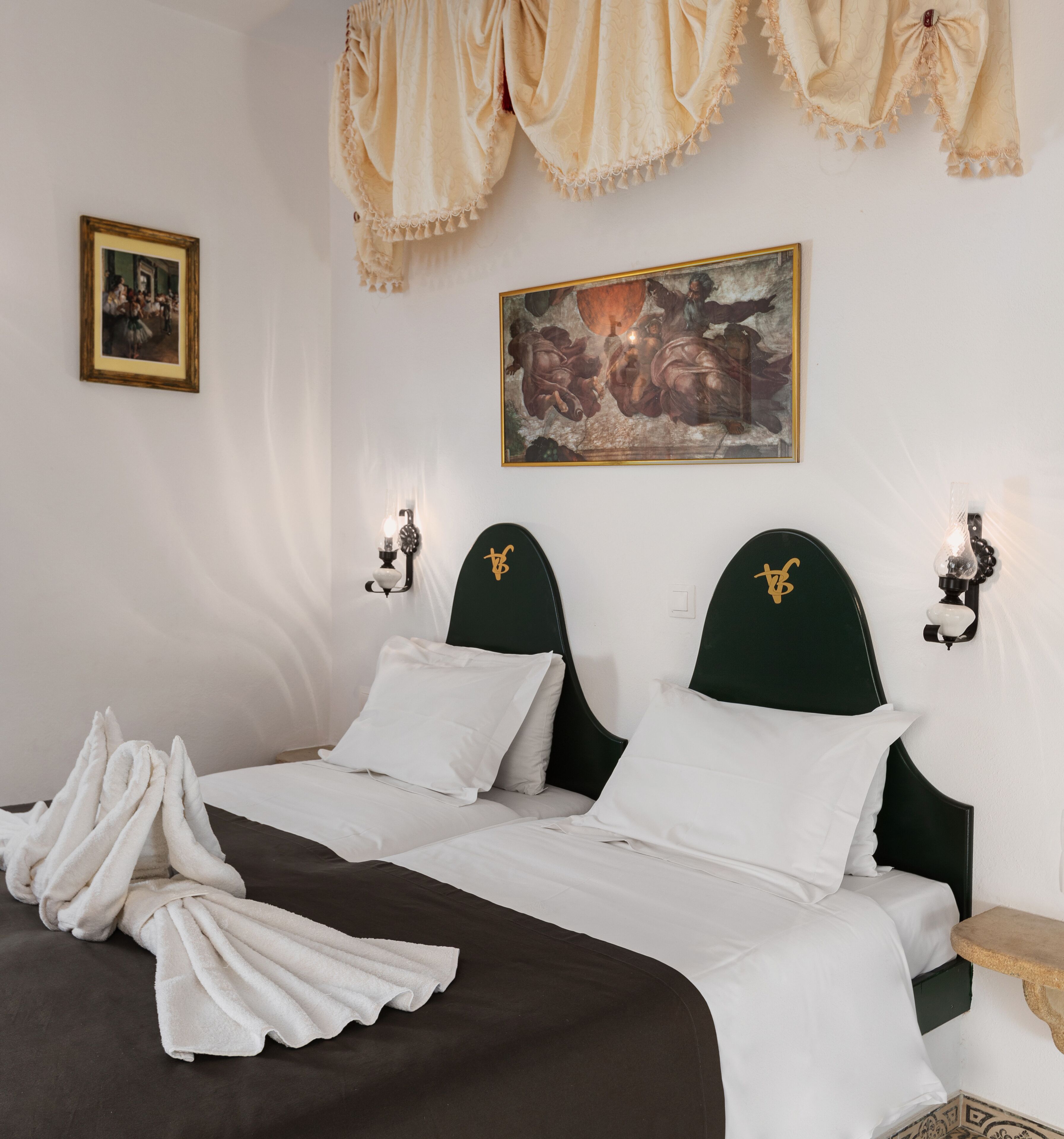 A hotel room with a bed, two bedside tables, a painting, and wall sconces.