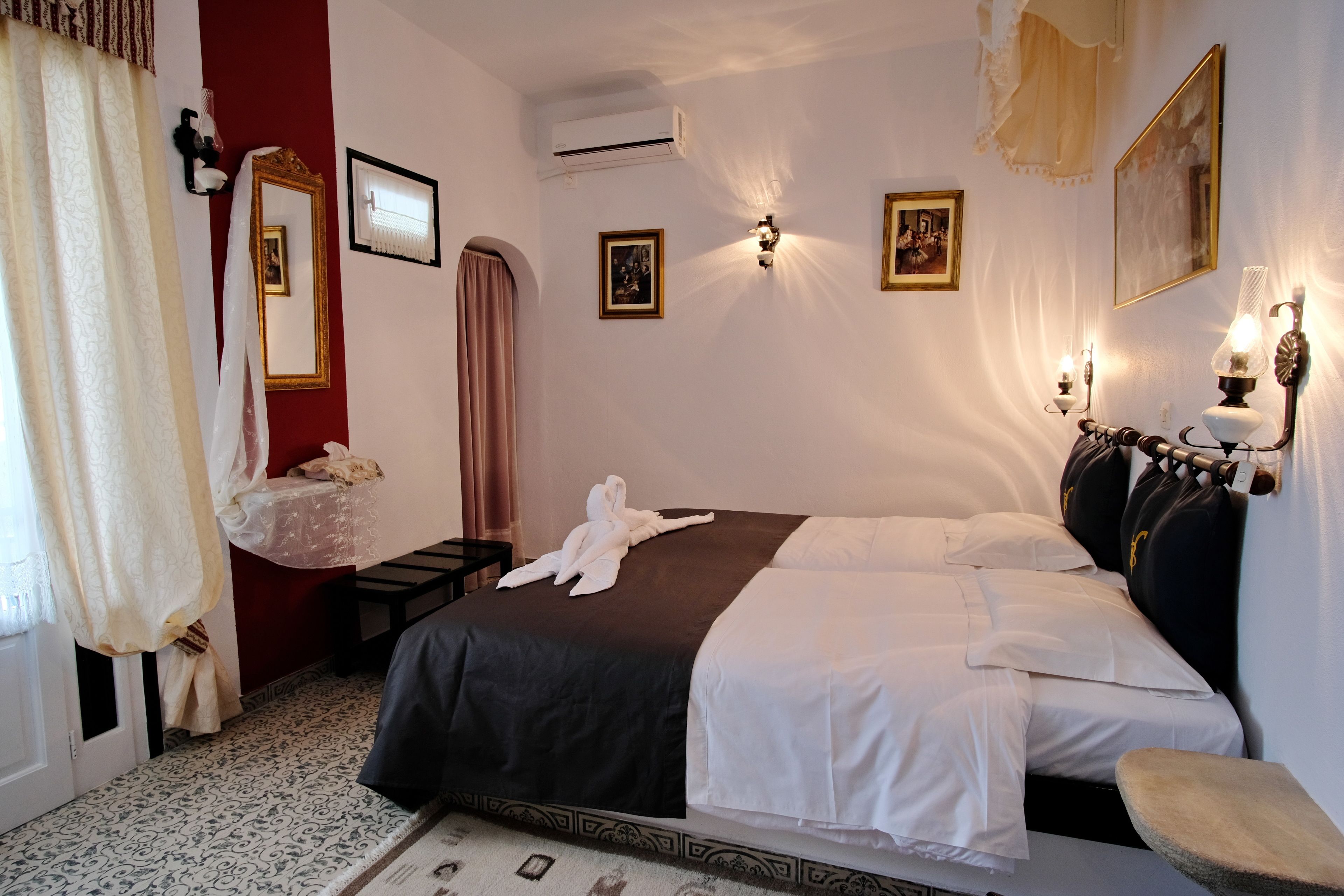 Una habitación de hotel con una cama grande, una mesita de noche, un espejo y luces en la pared.
