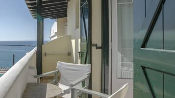 A balcony with a table and two chairs, overlooking the sea.