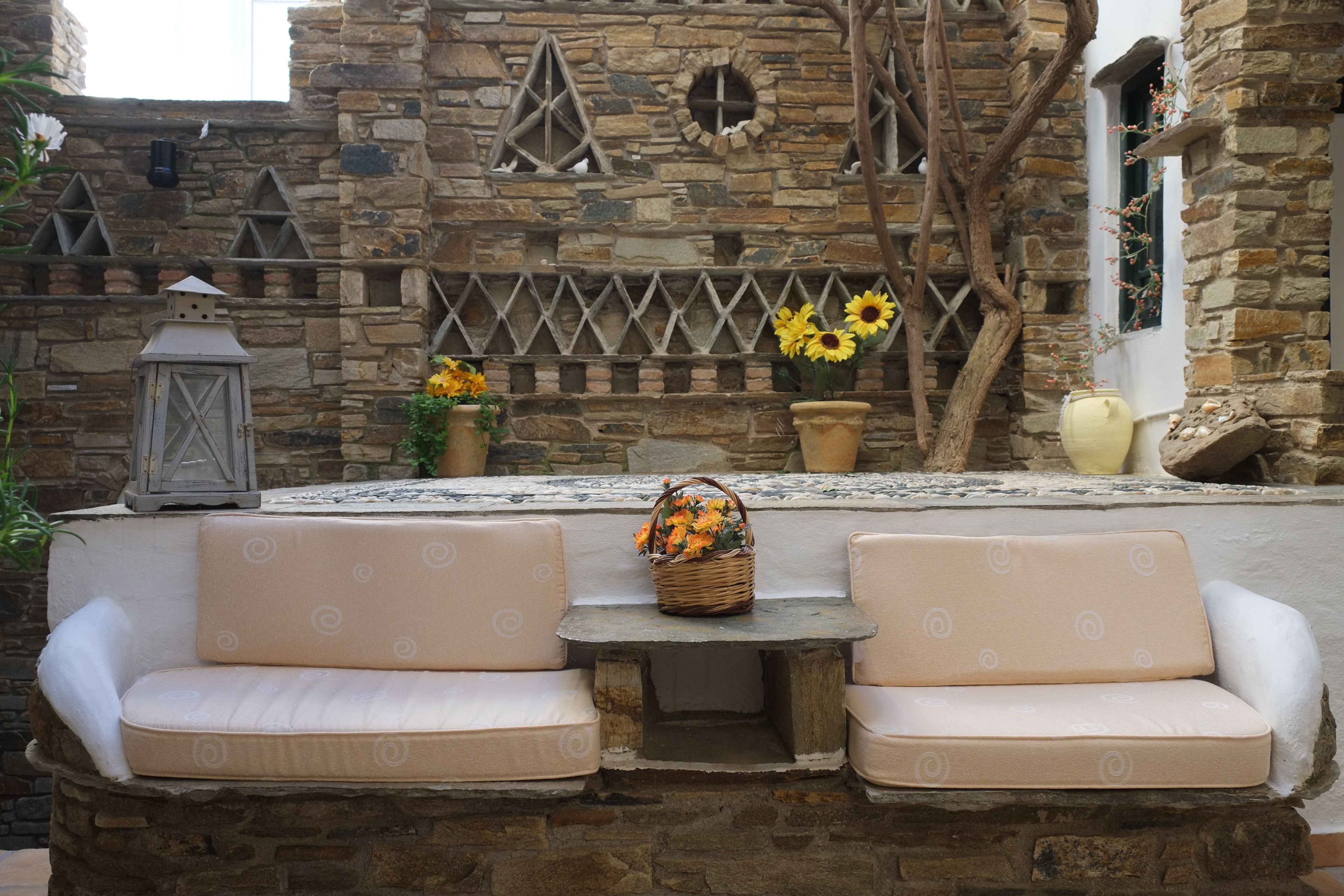 A stone wall with a built-in seating area, a stone table, and potted plants.