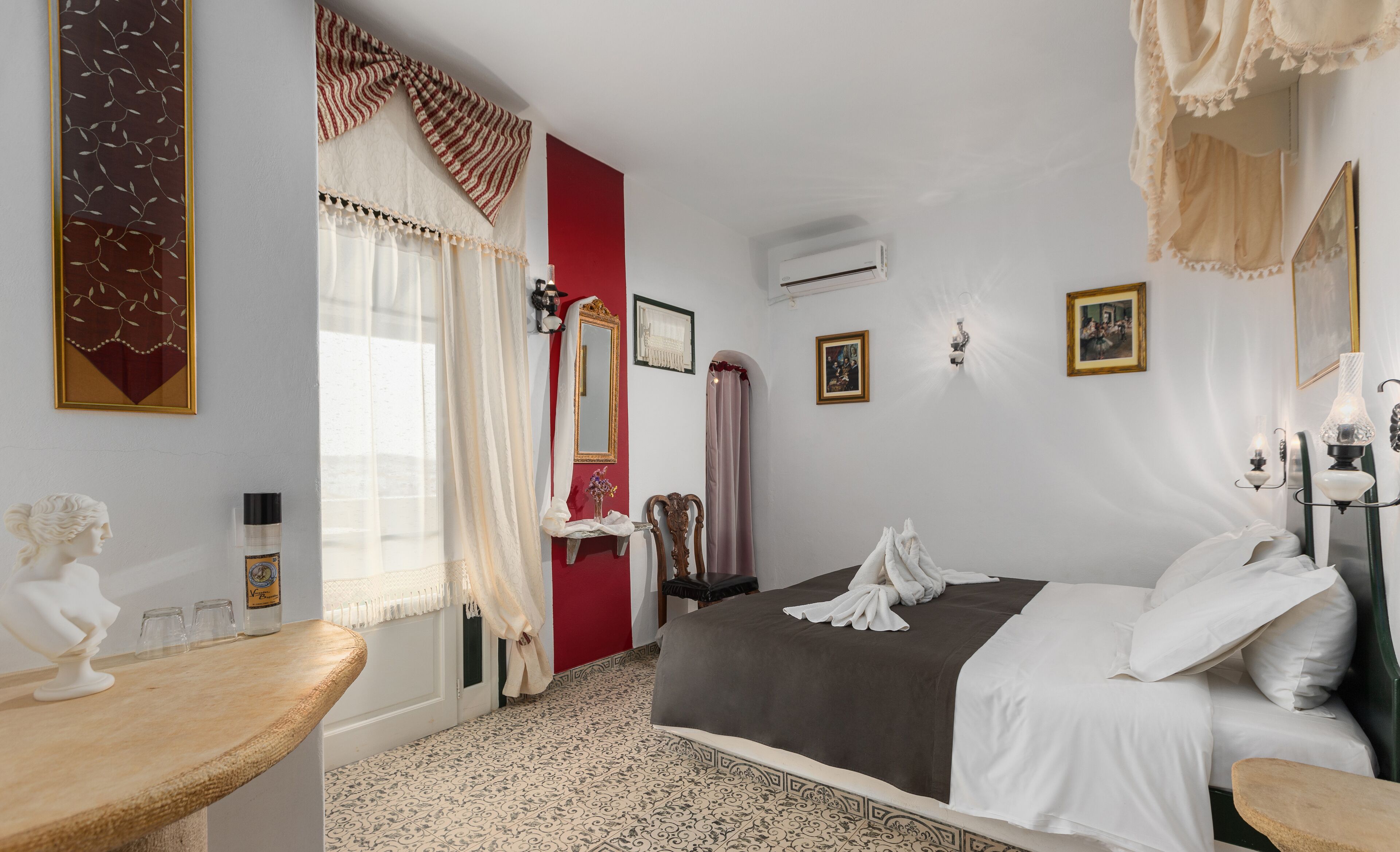 A hotel room with a bed, a vanity, a mirror, and a statue.