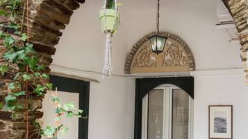 A room with a stone archway, a hanging planter, a table with chairs, and a window with a view.