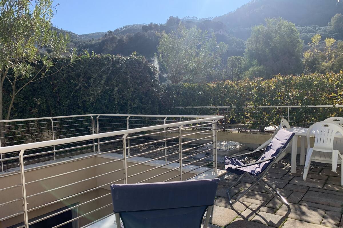 Une terrasse dotée d’une rambarde en métal, d’une chaise et d’une table recouverte d’une nappe.