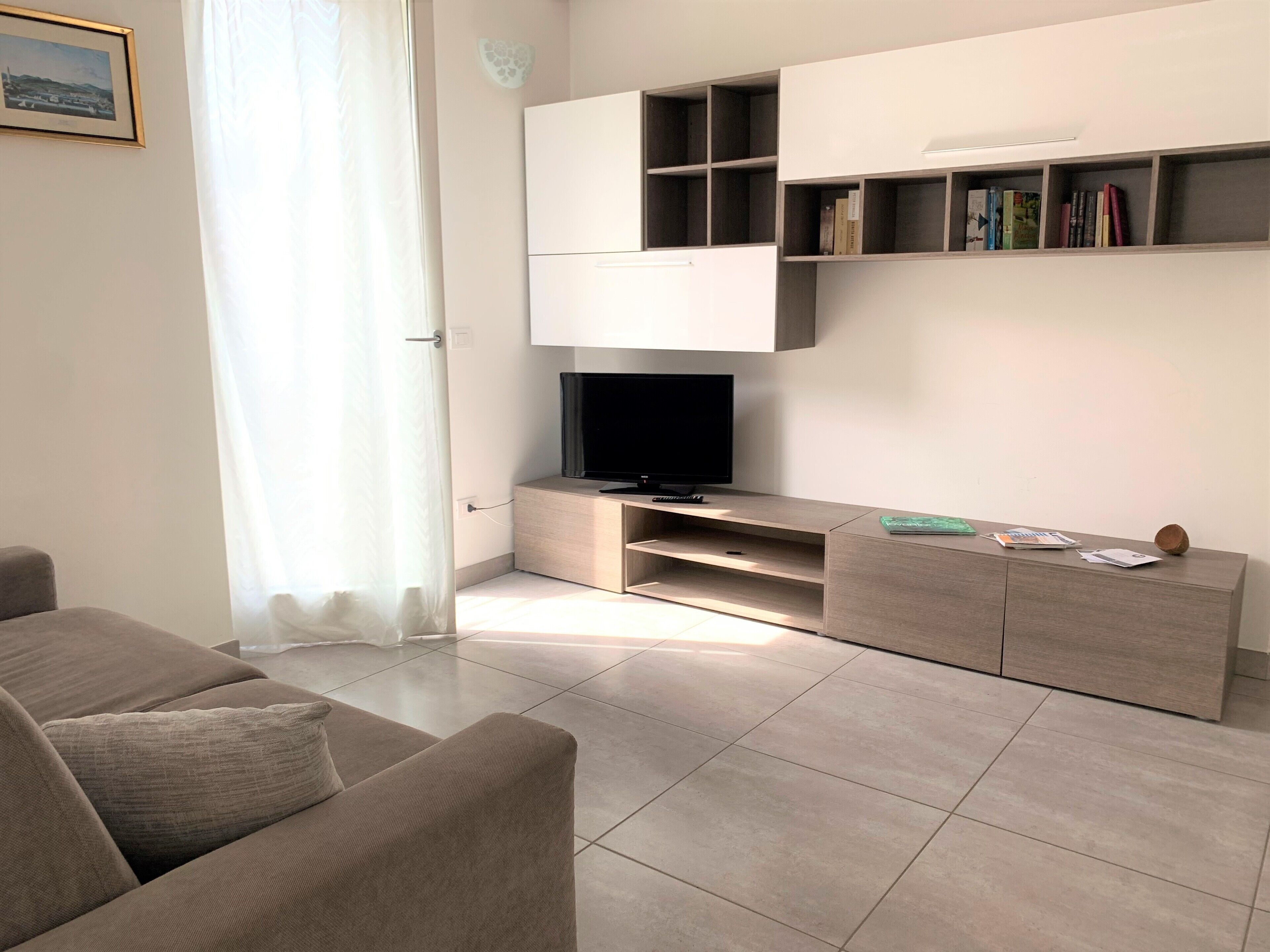 A modern living room with a sofa, TV, and built-in shelves.