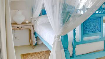 A bedroom with a four-poster bed, a nightstand, a lamp, and a decorative ceiling light.