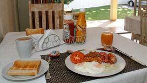 A breakfast table with toast, eggs, tomatoes, beans, sausages, ketchup, mustard, and a cup of coffee. - Coweys Corner (Durban)