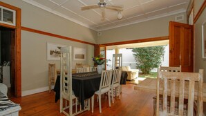 A dining area with a wooden table and chairs, a ceiling fan, and a view of the outdoors. - Coweys Corner (Durban)