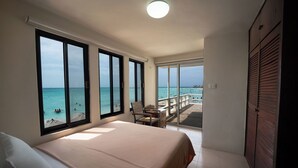 Un dormitorio con una cama grande, un escritorio y vistas a la playa y al océano.